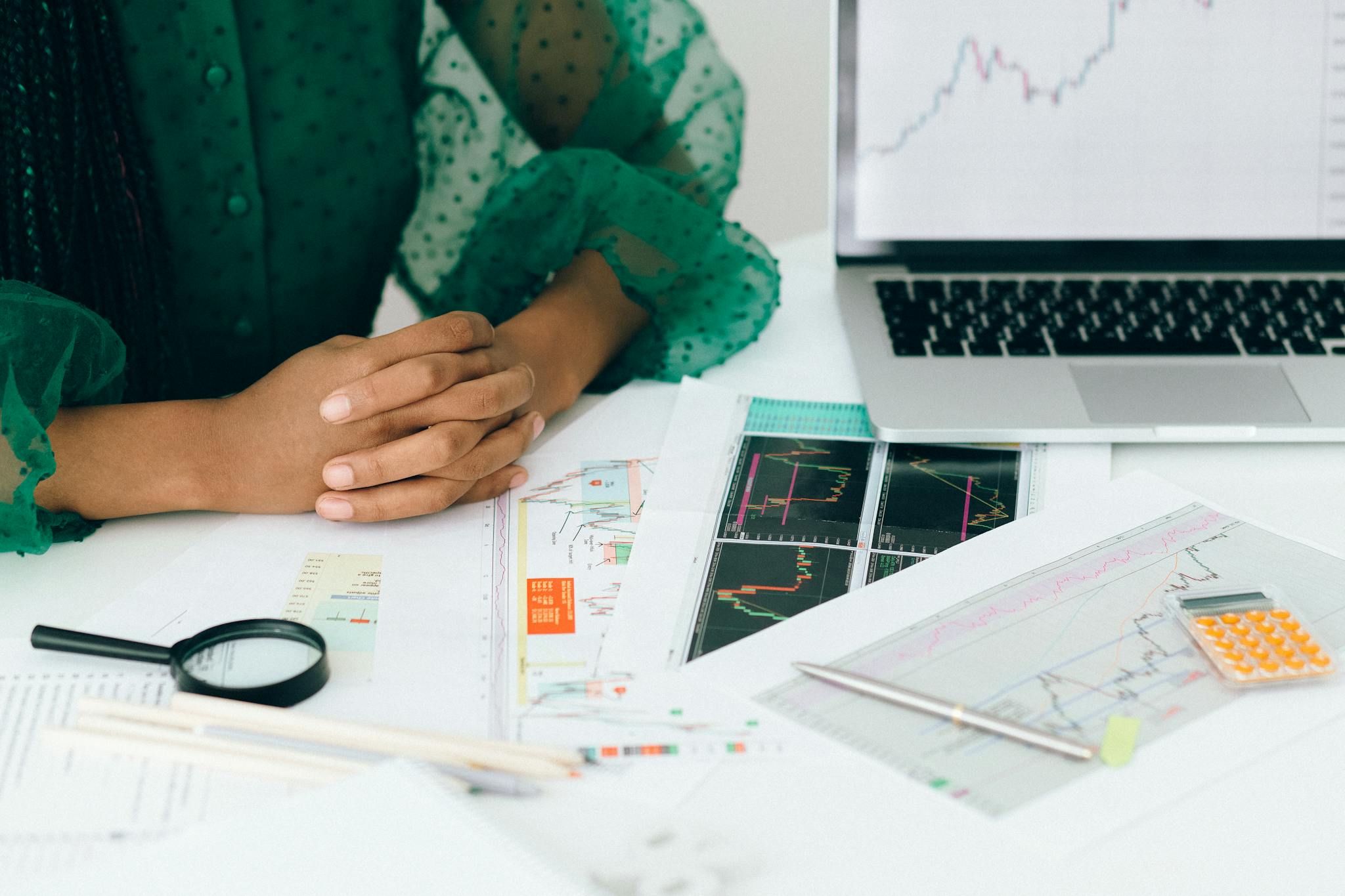 A person analyzes financial charts and graphs at a desk, indicating business trading activity.